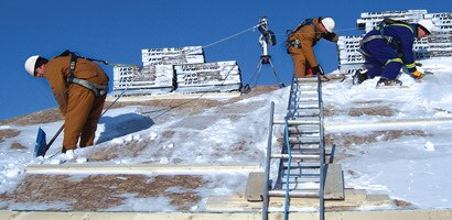 Workers on roof secured by fall protection gear
