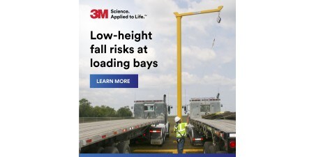 Front cover of a brochure showing a worker in a high-visibility vest & hard hat operating a yellow overhead hoist
