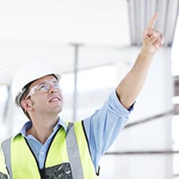 Two executives in hardhats at a renovation site look upward.