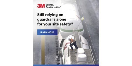 Front cover of a brochure showing a worker in a high-visibility vest & hard hat operating a yellow overhead hoist
