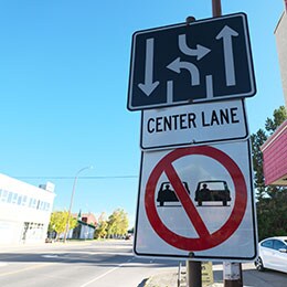 Road signs with diagram of three-lane road, words CENTER LANE and warning for vehicles not to drive side-by-side.