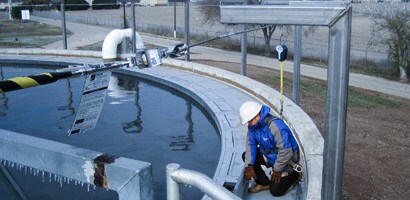 Worker on edge of large tank connected to fall protection anchorage
