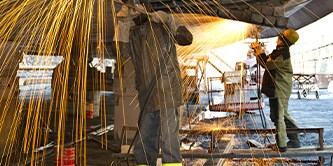 Two men welding a large vessel
