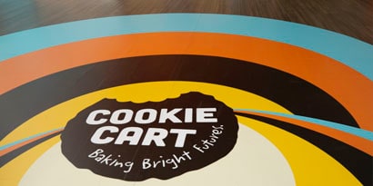 A floor graphic displays a colourful, circular branding design for 