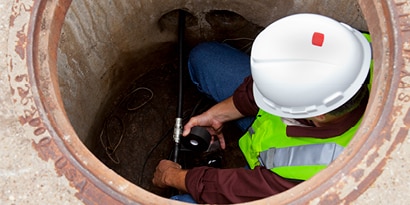 Electrician in manhole wrapping electrical connection.
