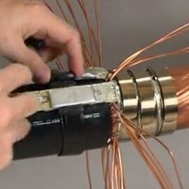 Video play button superimposed of hands pulling copper wires back on a 3M Cold Shrink QS-III Joint