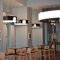 A café has round tables and hanging lamps.