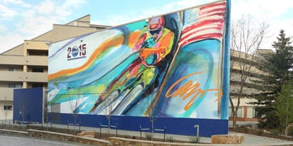 A large outdoor sign featuring a painted image of a bicyclist has bright colours protected by laminated film
