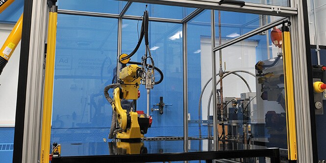 Image of a robot within a workframe, poised over a flat work table
