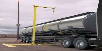 Photograph of a large silver tanker truck parked next to a yellow loading arm structure

