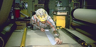 A man in construction wear is aligning film on a workstation
