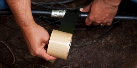 Worker wrapping large cable with 3M Rubber Mastic Tape
