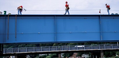 Workers atop steel structure connected to lifeline 