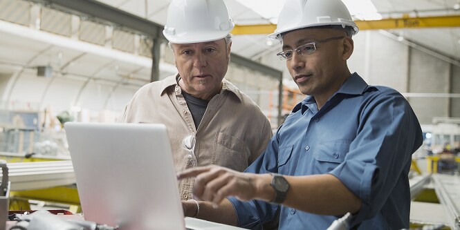 Two men discussing something in front of laptop
