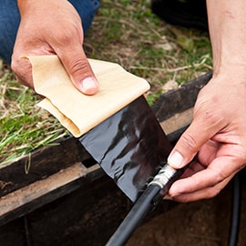 Image of 3M™ Scotch® Vinyl Mastic Tape 2200 wrapping a low voltage cable in an irrigation hole.