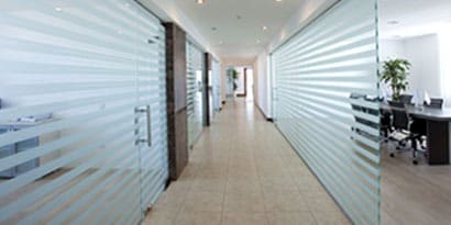 A long office hallway with glass graphic walls
