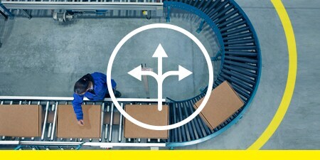 Top-down image of tape marking space around a U-bend conveyor with boxes; overlay of an icon representing flexibility
