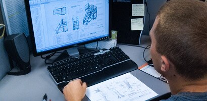 Engineer at computer looking at schematics of fall protection system
