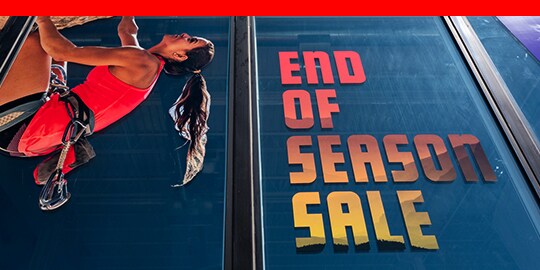 Large window graphic films showing rock climber and advertising sale.
