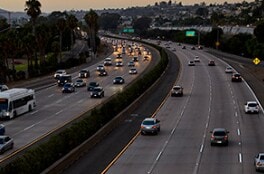 A busy eight-lane highway at dusk has easily viewable pavement markings