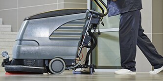Employee using a floor cleaning machine to polish a floor
