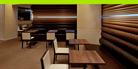 Retail space with tables and walls in a wood-grain surface finishes
