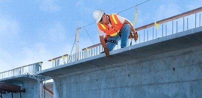 Worker on worksite wearing harness and fall protection gear

