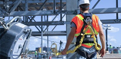 Worker on worksite wearing harness and fall protection gear
