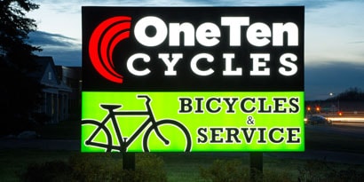 An illuminated sign for a bicycle shop is bright and colourful.
